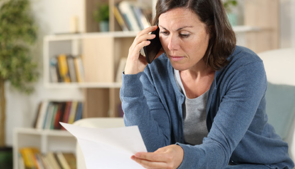 Frau liest Brief und telefoniert